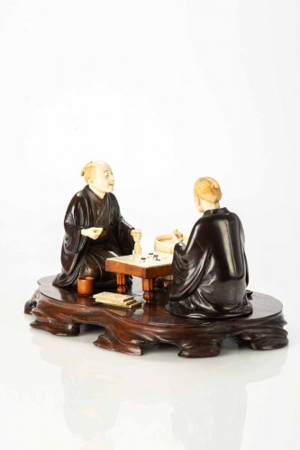 Asian Works of Art  - An Ivory and bronze okimono on a wooden base depicting two Go players