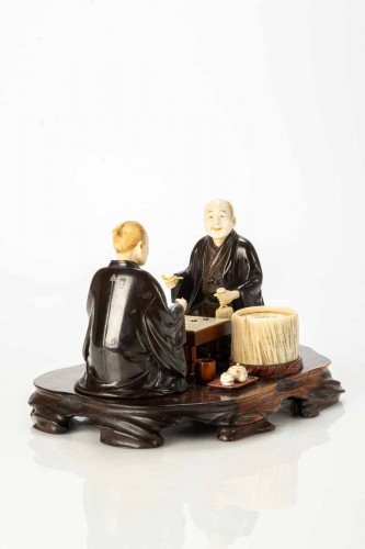 An Ivory and bronze okimono on a wooden base depicting two Go players - 
