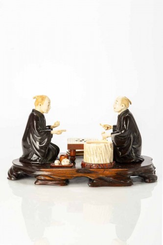 An Ivory and bronze okimono on a wooden base depicting two Go players - 