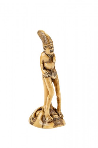 A shunga ivory netsuke depicting a monk seated on the nose of Tengu