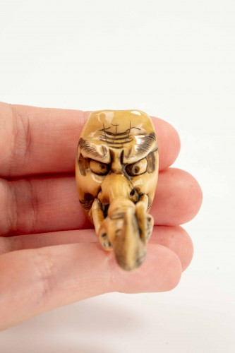  - A shunga ivory netsuke depicting a monk seated on the nose of Tengu