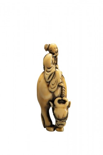 An ivory netsuke depicting Roshi seated on the back of a buffalo