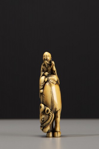 An ivory netsuke depicting Roshi seated on the back of a buffalo - Asian Works of Art Style 