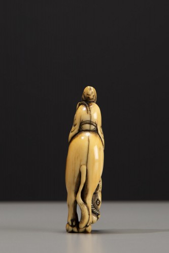 An ivory netsuke depicting Roshi seated on the back of a buffalo - 