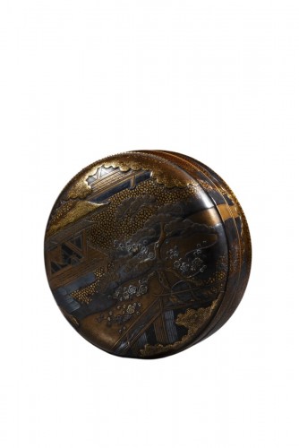 A circular gilt-lacquer box depicting a landscape scene