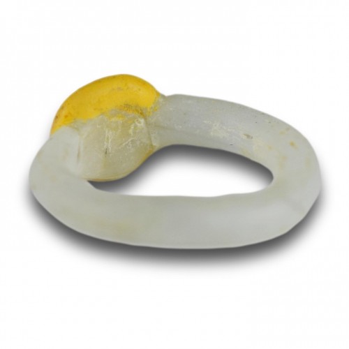 White glass ring with a yellow bezel and amber bead. Roman, 2nd-3rd Century - 