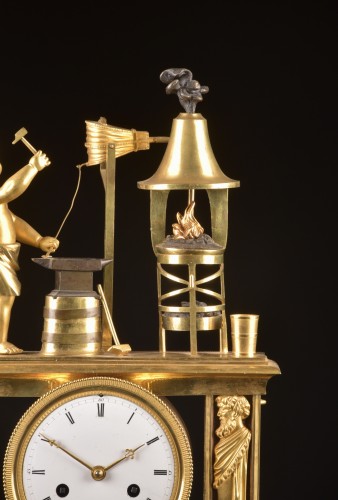 Cupidon forgeron - Pendule portique en bronze patiné et doré au feu d’époque Empire, - Mora Antiques