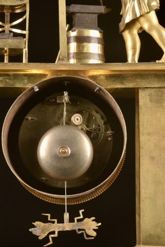 Empire - Cupidon forgeron - Pendule portique en bronze patiné et doré au feu d’époque Empire,