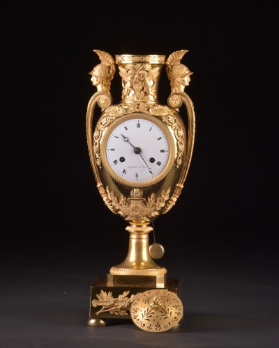 Vase pendule en plaqué or "Aux têtes de guerriers", circa 1810 - Mora Antiques