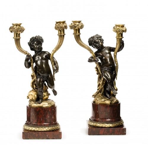 A pair of Louis XVI patinated and gilt bronze candelabra after a Clodion