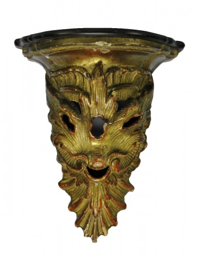 A carved and gilt wood wall bracket representing a foliated head